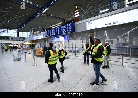 Stuttgart, Deutschland. 17. März 2023. Streikende Mitarbeiter des Stuttgarter Flughafens stehen mit Westen der Gewerkschaft Verdi in der leeren Abflughalle des Stuttgarter Flughafens. Flüge wurden wegen eines Verdi-Streiks gestrichen. Kredit: Bernd Weißbrod/dpa/Alamy Live News Stockfoto