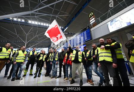 Stuttgart, Deutschland. 17. März 2023. Streikende Mitarbeiter des Stuttgarter Flughafens stehen mit Westen der Gewerkschaft Verdi in der leeren Abflughalle des Stuttgarter Flughafens. Flüge wurden wegen eines Verdi-Streiks gestrichen. Kredit: Bernd Weißbrod/dpa/Alamy Live News Stockfoto