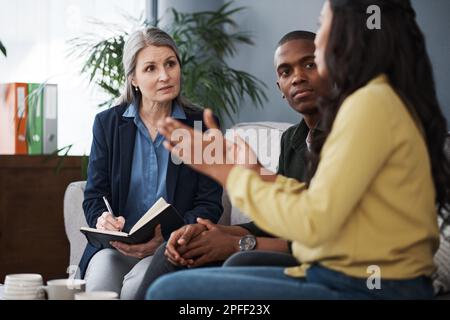 Sag mir, was deine Ziele sind. Ein Paar, das mit einem Finanzberater zu Hause spricht. Stockfoto