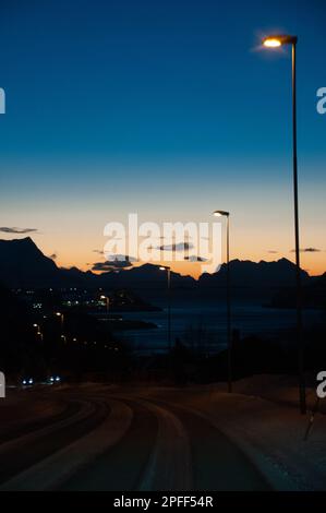 Eine einzige Straßenbeleuchtung beleuchtet eine Straße in Mittelnorwegen am frühen Abend der langen norwegischen Winter. Stockfoto