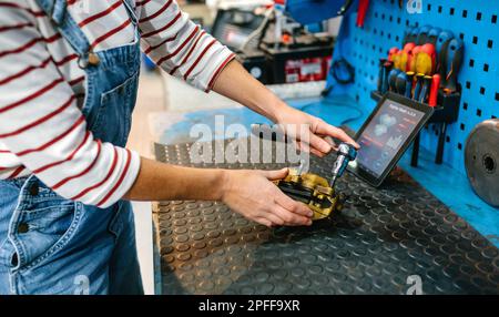 Mechanikerin, die das Bremssattel-Bremssystem über einer Werkbank repariert Stockfoto