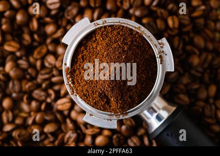 Draufsicht auf den Kaffeekocher-Halter mit Espresso-Kaffee, feinem Mahlwerk und ganzen gerösteten Bohnen, natürlicher Hintergrund Stockfoto