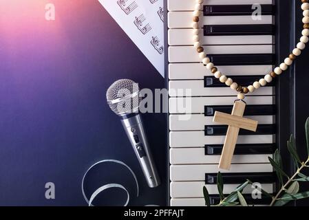 christlich-religiöses Konzertkonzept zu Ostern mit Klavier und Mikrofon auf schwarzem Hintergrund mit rotem Rampenlicht. Draufsicht. Stockfoto