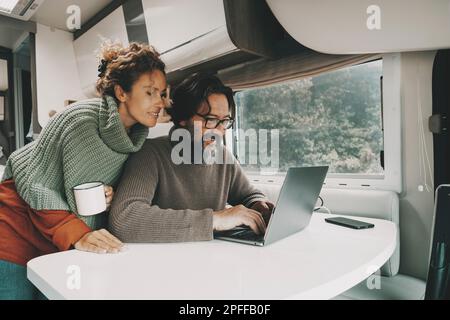 Ein Paar bei der Arbeit mit einem Laptop im Wohnmobil, alternativer Job und Lebensstil. Mann und Frau, die einen Computer im Innenbereich benutzen Stockfoto