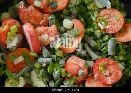 Gefrorenes frisches Gemüse, das zu Hause in einer heißen Pfanne gekocht wird. Gesunde und natürliche Zutaten für kalorienarme Ernährung Stockfoto