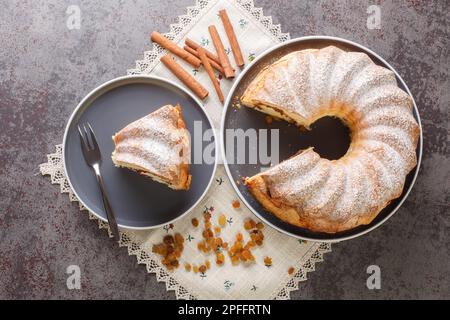 Hausgemachter Oster-Reindling-Kuchen mit Rosinen und Zimt in Nahaufnahme auf einem Teller auf dem Tisch. Horizontale Draufsicht von oben Stockfoto