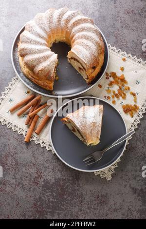 Festlicher Reindling-Kuchen mit Rosinen und Zimt in Nahaufnahme auf einem Teller auf dem Tisch. Vertikale Draufsicht von oben Stockfoto