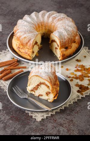 Festlicher Reindling-Kuchen mit Rosinen und Zimt in Nahaufnahme auf einem Teller auf dem Tisch. Vertikal Stockfoto