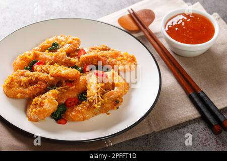 Gebratene Garnelen im asiatischen Stil mit gesalzenem Eigelb, Curryblättern und Chili, serviert mit Chilisauce aus nächster Nähe auf einem Teller auf dem Tisch. Horizontal Stockfoto