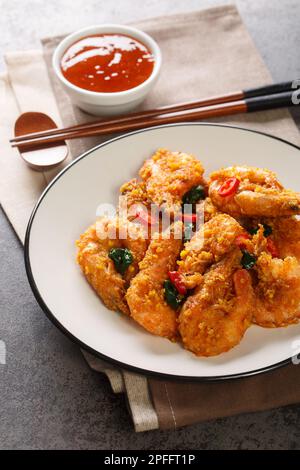 Gebratene Garnelen mit gesalzenem Eigelb, Curryblättern und Chili-Pfeffer in Nahaufnahme auf einem Teller auf dem Tisch. Vertikal Stockfoto