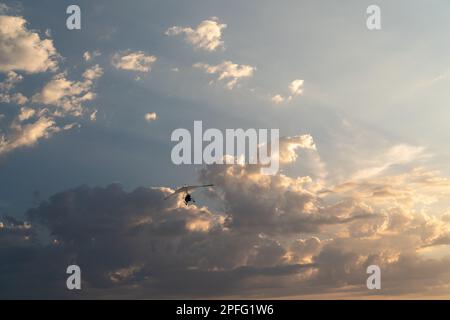 Das Propellerflugzeug fliegt am Sonnenuntergang. Ein kleiner privater Drachenflieger in einem bewölkten Himmel. Stockfoto