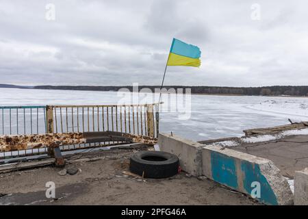 Die ukrainische Flagge kann man auf der durch den Krieg beschädigten Brücke über den Siverskyi Donets River in Staryi Saltiv, Charkiv, sehen Stockfoto