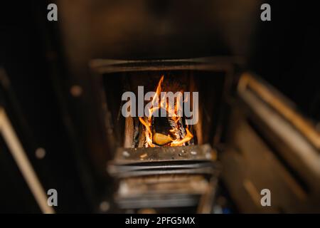 Holz, das in schwarzem Kachelofen verbrannt ist, heizt das Haus während die Gaspreise steigen Stockfoto