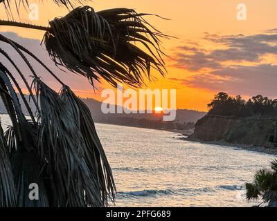 Santa Barbara, Kalifornien, USA. 16. März 2023. Ein goldener Sonnenuntergang bricht durch die schweren Wolken und bildet ein rotes „Auge“ auf einer Palme am Butterfly Beach, Montecito CA, nach dem jüngsten stimmungsvollen Flusssturm. (Kreditbild: © Amy Katz/ZUMA Press Wire) NUR REDAKTIONELLE VERWENDUNG! Nicht für den kommerziellen GEBRAUCH! Stockfoto