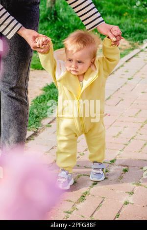 Die ersten Schritte des Babys mit der Hilfe der liebevollen Mutter Stockfoto