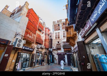 Blick auf einen kleinen Platz, umgeben von hohen traditionellen Korallenhäusern mit Geschäften und Geschäften im historischen Al-Balad in Jeddah, KSA, Saudi-Arabien Stockfoto