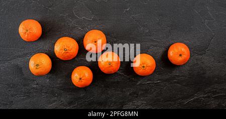 Blick von oben, Mandarinen oder Mandarinen auf schwarzem Schieferbrett Stockfoto
