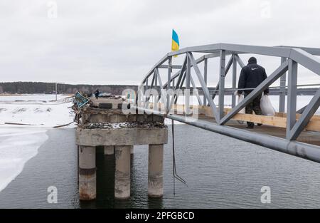 Vorübergehend restaurierte Fußgängerzone über eine zerstörte Brücke über den Siverskyi Donets River in Staryi Saltiv, Region Charkiv. Folgen des Angriffskrieges der Russischen Föderation in der ukrainischen Charkiv-Region. Zerstörte Häuser, Brücken, Stromleitungen. Nach der Aufhebung der Besetzung wird das Leben wieder aufgebaut, und die Ukrainer bauen aktiv wieder auf, was wieder aufgebaut werden kann. Stockfoto