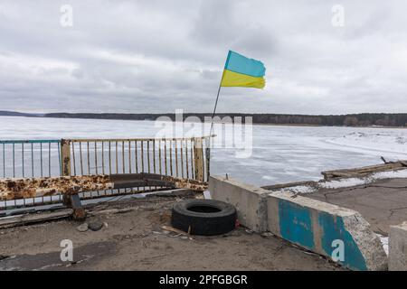 Die ukrainische Flagge kann man auf der durch den Krieg beschädigten Brücke über den Siverskyi Donets River in Staryi Saltiv, Charkiv, sehen. Folgen des Angriffskrieges der Russischen Föderation in der ukrainischen Charkiv-Region. Zerstörte Häuser, Brücken, Stromleitungen. Nach der Aufhebung der Besetzung wird das Leben wieder aufgebaut, und die Ukrainer bauen aktiv wieder auf, was wieder aufgebaut werden kann. (Foto: Mykhaylo Palinchak / SOPA Images/Sipa USA) Stockfoto