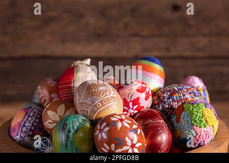 Blick von der Seite einer Holzschüssel, gefüllt bis zum Rand mit bunten Ostereiern. Stockfoto