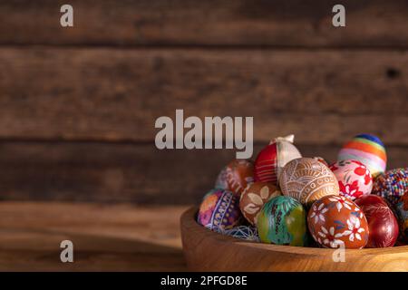 Blick von der Seite einer Holzschüssel, gefüllt bis zum Rand mit bunten Ostereiern. Stockfoto