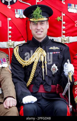 Der Prinz von Wales lächelt, während er sich für ein Gruppenfoto bei einem Besuch der 1. Battalion Irish Guards für die St. Patrick's Day Parade in der Mons Barracks in Aldershot setzt. Foto: Freitag, 17. März 2023. Stockfoto