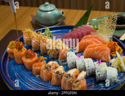 Kombiniert mit verschiedenen japanischen Sushi auf einem eleganten blauen Teller. Stockfoto