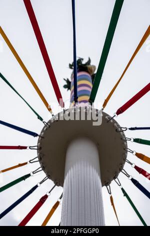 Ein kleiner Winkel eines klassischen englischen Maypole während eines Tanzfestivals unter bewölktem Himmel Stockfoto