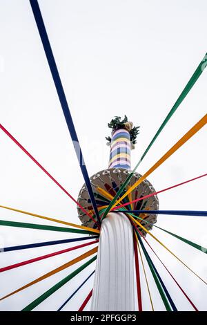 Ein kleiner Winkel eines klassischen englischen Maypole während eines Tanzfestivals unter bewölktem Himmel Stockfoto