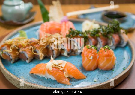 Kombiniert mit verschiedenen japanischen Sushi auf einem eleganten blauen Teller. Stockfoto