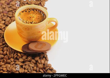 tasse Kaffee und Bohnen auf weißer Oberfläche mit runden Schokoladen Stockfoto