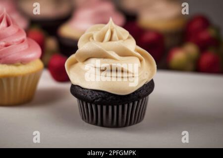 Zwei frische, leckere Cupcakes, Schokoladen-Muffin, Vanillecreme und Kekse, rosa Beerencreme Stockfoto