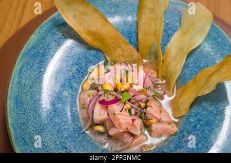 Köstliche Lachs-Ceviche mit Gemüse, Gewürzen und Zitrone auf einem Teller auf dem Tisch. Horizontale Draufsicht von oben Stockfoto