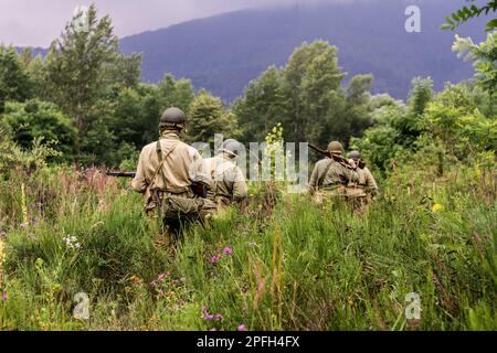 Porabka, Polen – July18, 2020 : Historischer Wiederaufbau. Im Zweiten Weltkrieg patrouillieren amerikanische Infanteriesoldaten im hohen Gras. Ansicht von der Stockfoto