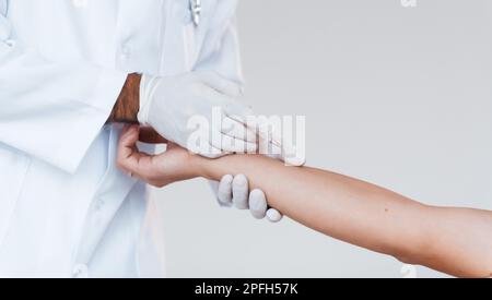 Der Arzt arbeitet mit der Hand des Patienten. Nahaufnahme eines jungen Mannes, der drinnen vor weißem Hintergrund steht Stockfoto