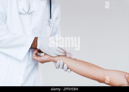 Der Arzt arbeitet mit der Hand des Patienten. Nahaufnahme eines jungen Mannes, der drinnen vor weißem Hintergrund steht Stockfoto