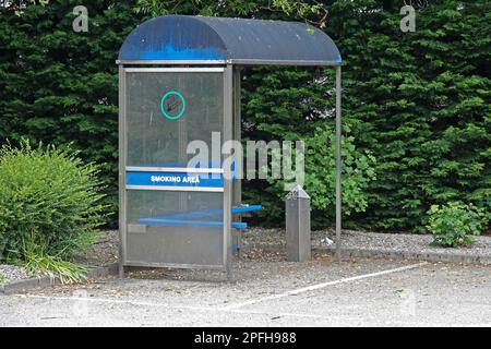 Tagsüber befindet sich in der Ecke eines Parkplatzes ein Bereich, der für einen Raucherbereich reserviert ist. Stockfoto