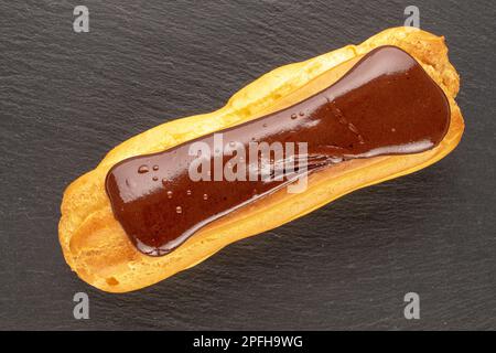 Ein Schokoladen-eclair, Nahaufnahme, auf einem Schieferstein, Draufsicht. Stockfoto