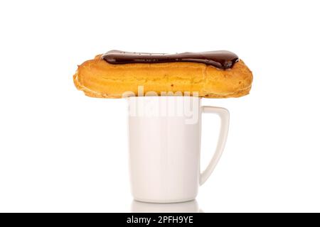 Ein süßes Schokoladen-eclair mit einem weißen Becher, Nahaufnahme, isoliert auf weißem Hintergrund. Stockfoto