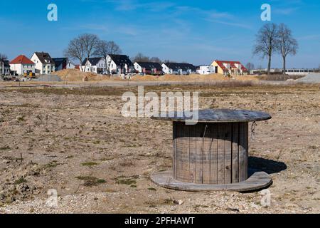 Große Holzrolle ohne Kabeldraht im Außenbereich. Unterbringung im Hintergrund. Stockfoto