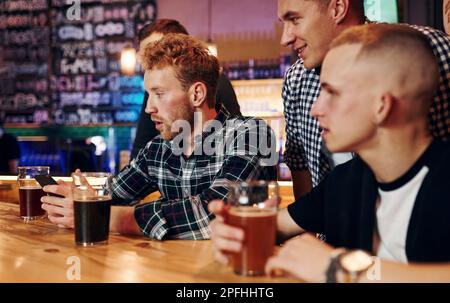 Eine Gruppe von Leuten zusammen im Pub hat am Wochenende Spaß Stockfoto