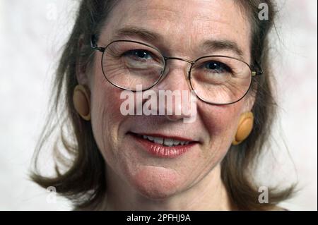 Nahaufnahme des Porträts einer Weißen mittleren Alters, die eine Brille trägt, vergrößert die Ohrringe auf weißem Hintergrund Stockfoto