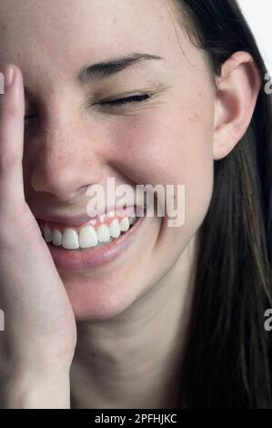 Nehmen Sie eine andere junge weiße Frau auf, die lächelt, lacht oder sich schämt Stockfoto