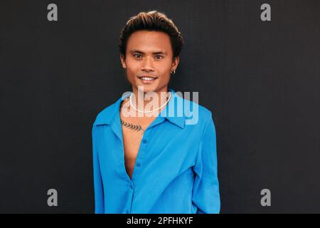 Porträt eines jungen, gutaussehenden Kerls, einer schwarzen Wand, die in die Kamera schaut Stockfoto