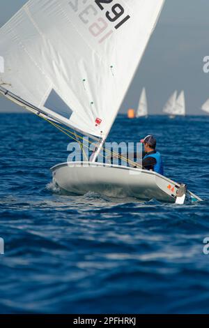 Foto eines Teenagers, der auf einem Laser-Segelboot mit Segeln im Hintergrund segelt Stockfoto