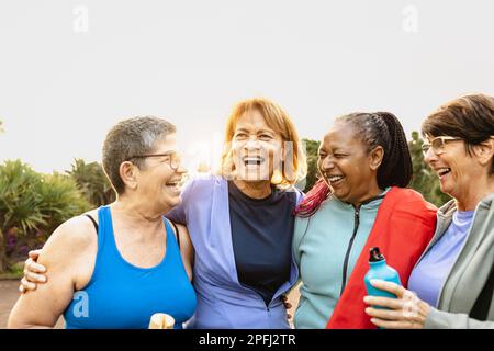 Fröhliche, multiethnische Seniorinnen, die nach dem Training im Park Spaß haben Stockfoto