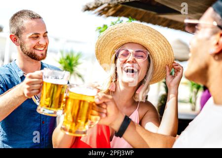 Trendige, glückliche Freunde, die Bier in der Chiringuito Beach Bar anstoßen - Sommerferienkonzept mit jungen Leuten, die sich an einem sonnigen Tag Zeit miteinander verbringen Stockfoto