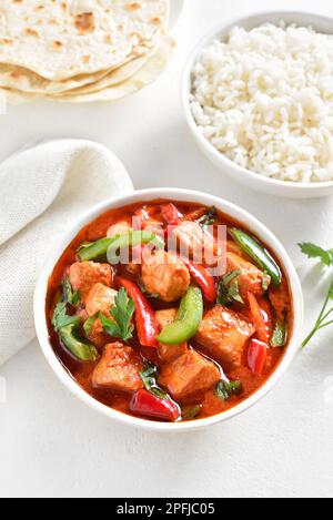 Thailändisches rotes Hühnercurry mit Gemüse in der Schüssel auf weißem Steinhintergrund. Stockfoto