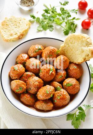 Fleischbällchen mit Tomatensauce in einer Schüssel auf weißem Steingrund. Nahaufnahme Stockfoto