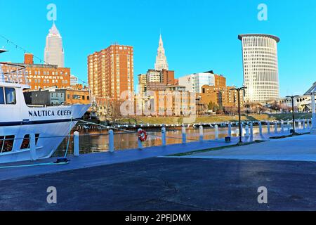 Die Nautica Queen liegt am Westufer des Cuyahoga River und die Sonne geht am Ostufer in den Flats in Cleveland, Ohio, USA unter. Stockfoto